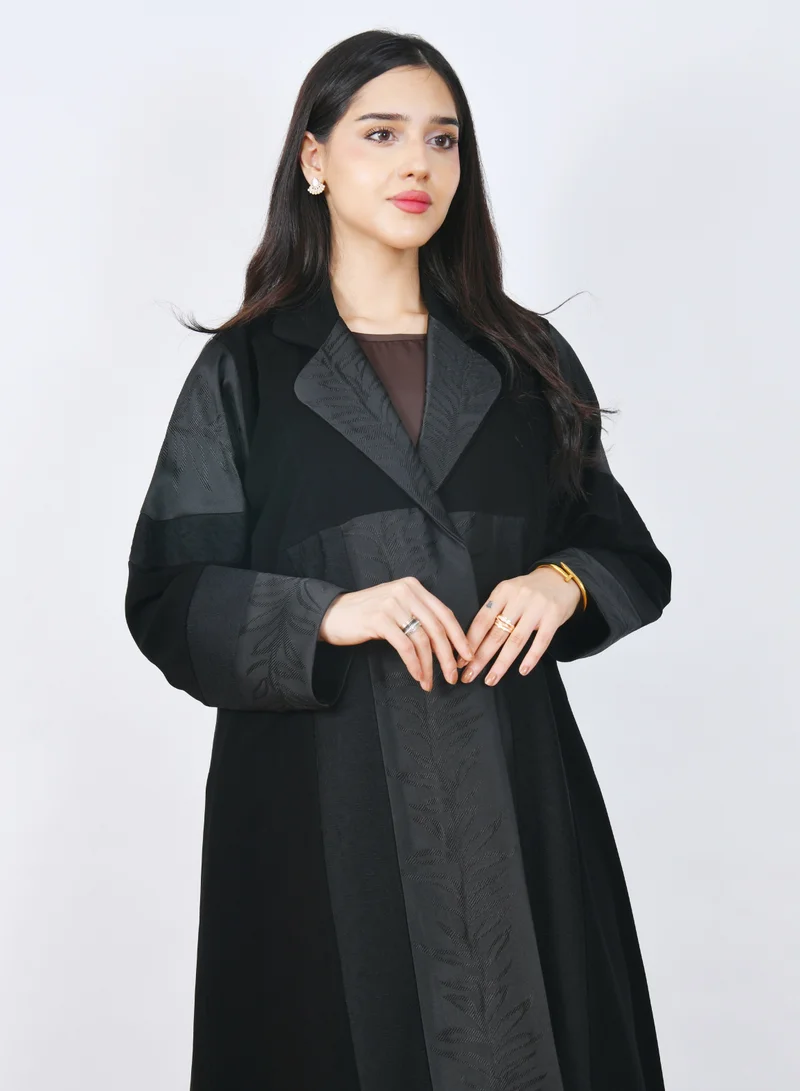 HAWRAA ABAYA Luxurious black abaya with a half-flared design, featuring jacquard patterned fabric on the front and sleeves with an elegant collar.