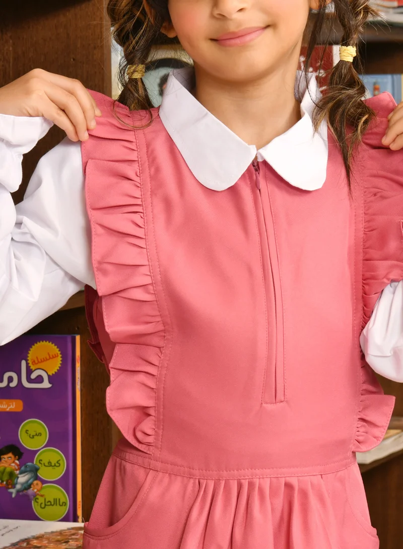 HAWRAA ABAYA Pink apron with long sleeves, ruffles on the shoulders, a zipper closure on the front, pleats at the bottom, and a tightening tie