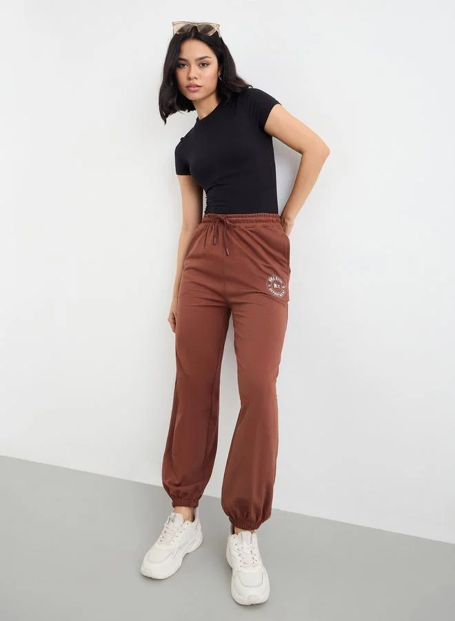 Styli Styli Brown Tapered Joggers with Graphic Print