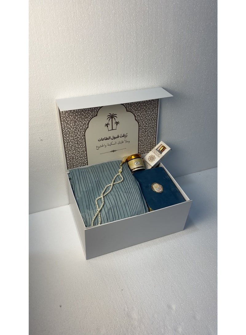 The comprehensive 6-piece prayer set (in "Hiba Blue") is an elegant and practical gift that combines reverence with comfort; it includes a padded prayer mat, a pleated prayer gown, a Quran, prayer beads, *mabthouth* (incense blend), and musk. - Image 1