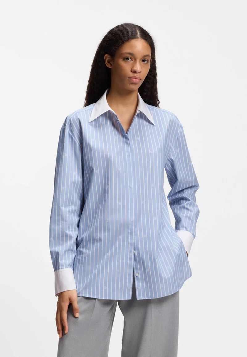 هوجو بلوزة بقصة واسعة وشعارات مكدسة