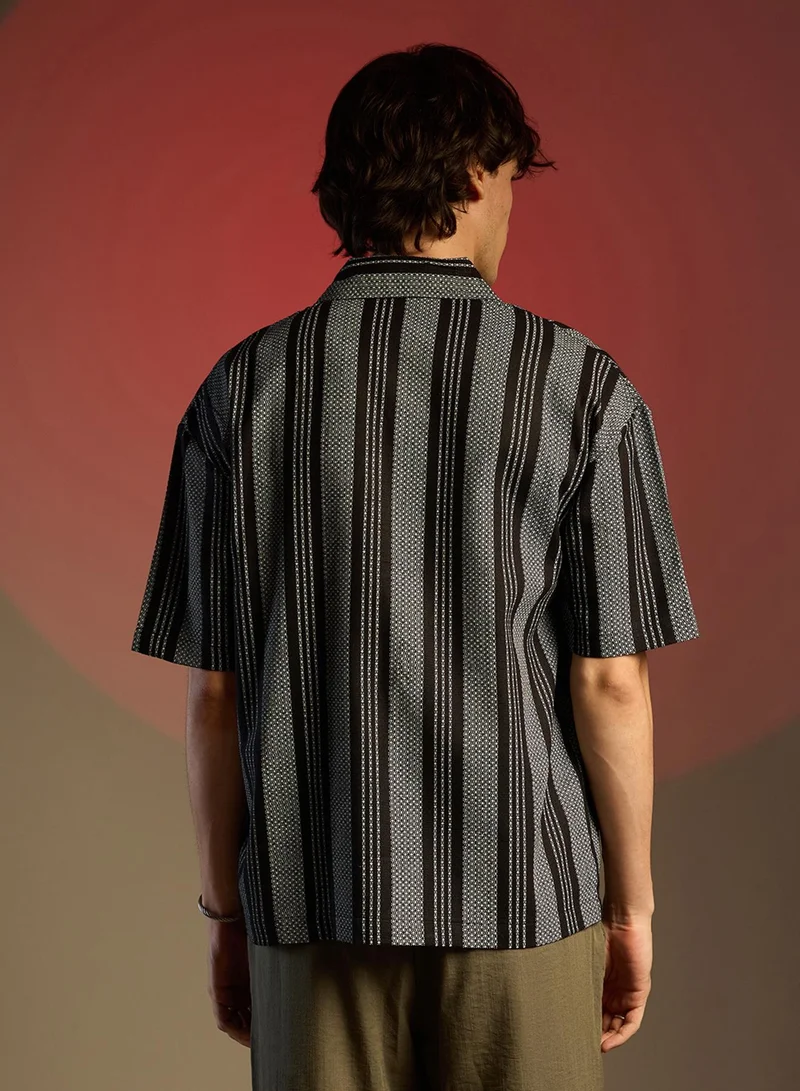 Campus Sutra Campus Sutra Men's Obsidian Black Woven Striped Oversized Shirt For Casual Wear | Cuban Collar | Short Sleeve | Button Closure | Oversized Shirt Crafted With Comfort Fit For Everyday Wear