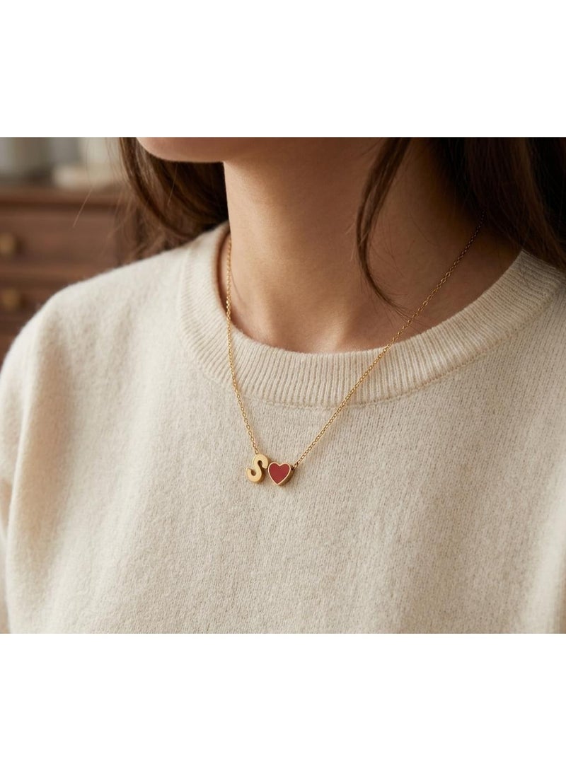Luxuria A delicate necklace featuring an "S" pendant alongside a small, bright red heart charm, both in lustrous gold. This necklace is typically made of stainless steel. - Image 2