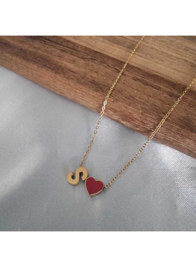 Luxuria A delicate necklace featuring an "S" pendant alongside a small, bright red heart charm, both in lustrous gold. This necklace is typically made of stainless steel. - Image 1