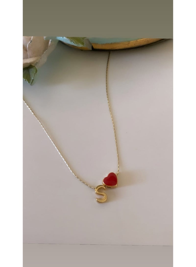 Luxuria A delicate necklace featuring an "S" pendant alongside a small, bright red heart charm, both in lustrous gold. This necklace is typically made of stainless steel. - Image 4