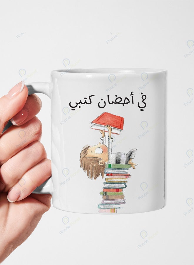 كوب من السيراميك مطبوع عليه عبارة في أحضان كتبي ويتميز بمقبض مريح