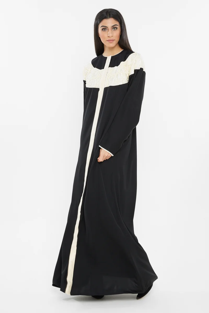 النخبة A rich black abaya with an off white boat neck patch by the neckline ; embroidered with white pearls -AJ61A