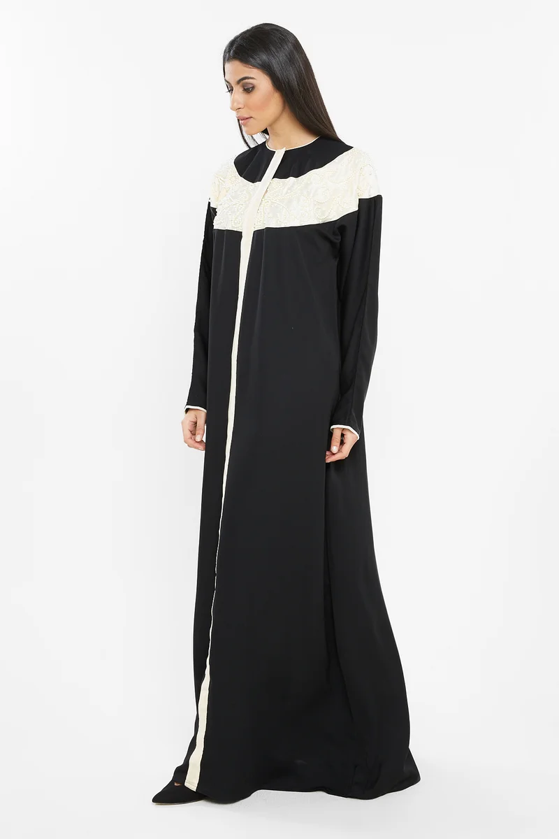 النخبة A rich black abaya with an off white boat neck patch by the neckline ; embroidered with white pearls -AJ61A