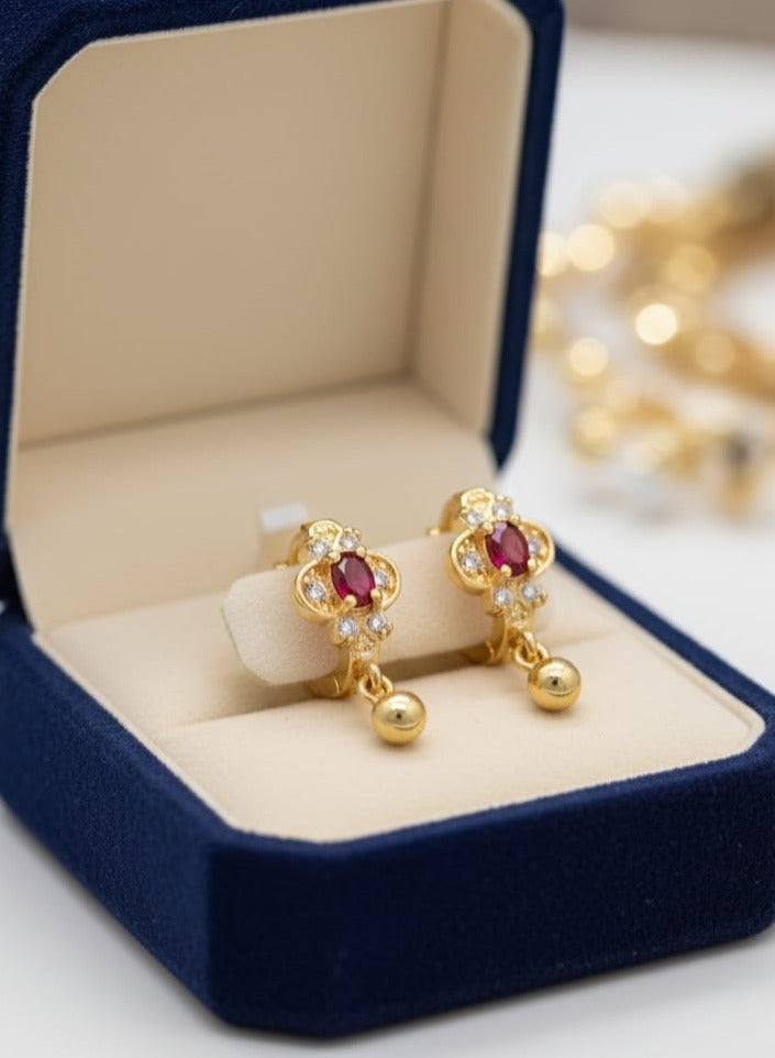 A delicate gold-plated hoop featuring a crimson red centerpiece, surrounded by the sparkle of dazzling white zircon stones. The allure is completed with a small spherical pendant. - Image 1