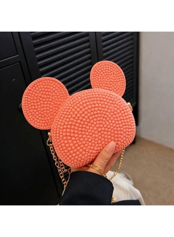 Girls' mini round crossbody bag with a cute cartoon ear design. Made of flexible silicone material with a raised bubble texture surface in a peach-orange color. It features a metal chain strap for shoulder or hand carrying and a top zipper closure to keep small items like coins or accessories secure. Suitable for daily use and outings.