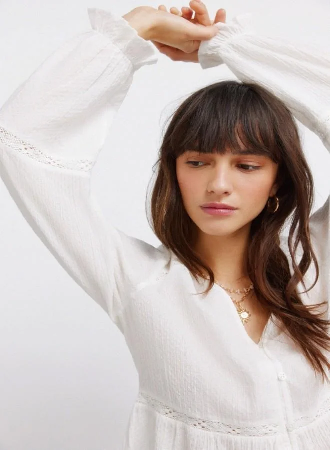 Springfield  White long sleeve blouse. V-neck. Front buttons. Waist with ruffle. Lace detail on the yoke, sleeves, waist and hem. Cuffs with elasticated trim and ruffles. This garment is made from sustainable cotton. for Women | Best Price UAE