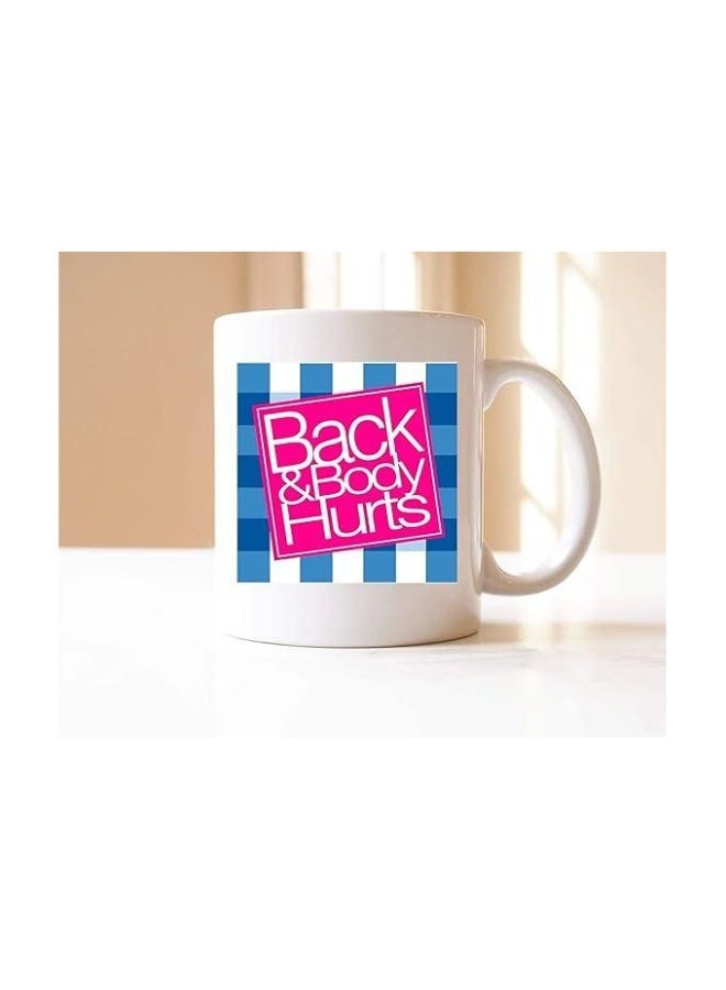 مج سيراميك أبيض مطبوع بجملة "ظهر وجسم يؤلم" لإضافة لمسة مرحة على صباحك.