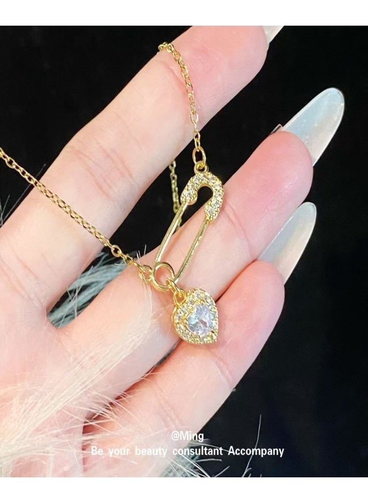 World Luxury Elegant gold necklace with a safety pin and studded heart design - a touch of soft luxury - Image 1