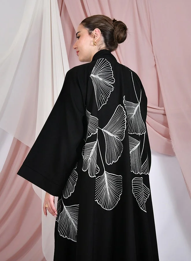 HAWRAA ABAYA Black flared abaya with wide sleeves, featuring elegant white embroidery across the entire abaya