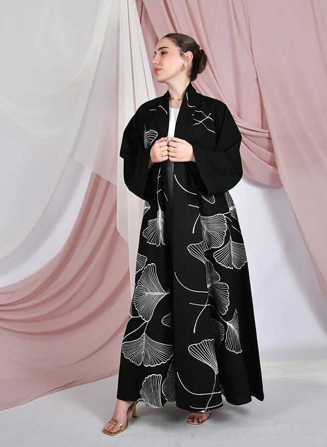 HAWRAA ABAYA Black flared abaya with wide sleeves, featuring elegant white embroidery across the entire abaya
