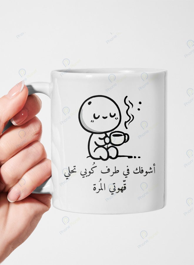 كوب من السيراميك مطبوع عليه عبارة أشوفك في طرف كوبي تحلى قهوتي المرة ويتميز بمقبض مريح