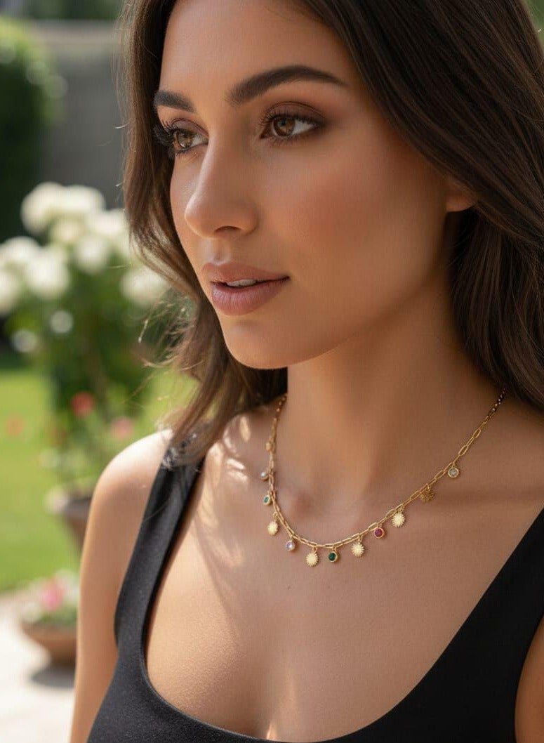 Luxuria This striking gold chain necklace features a modern design combining sun-shaped pendants and colorful gemstones. The chain itself is made of thick links, giving it a distinctive look. - Image 1