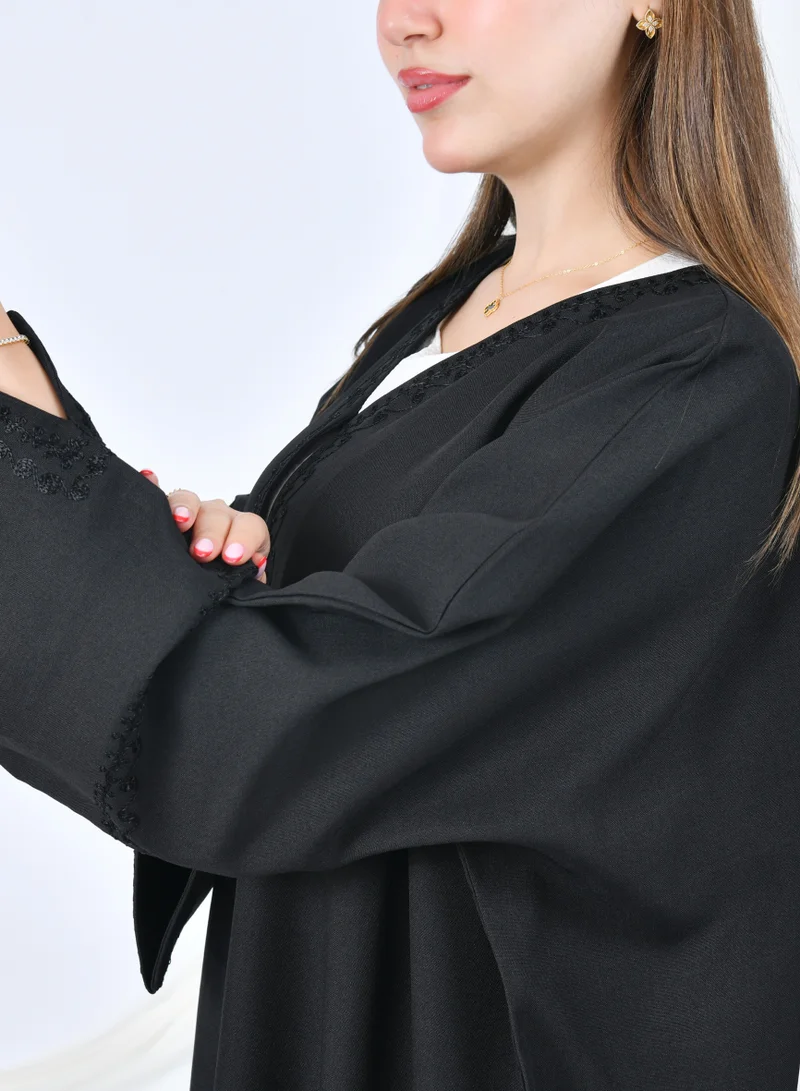 HAWRAA ABAYA Black abaya with a quarter bisht design, decorated with delicate embroidery on the edges and sleeves.