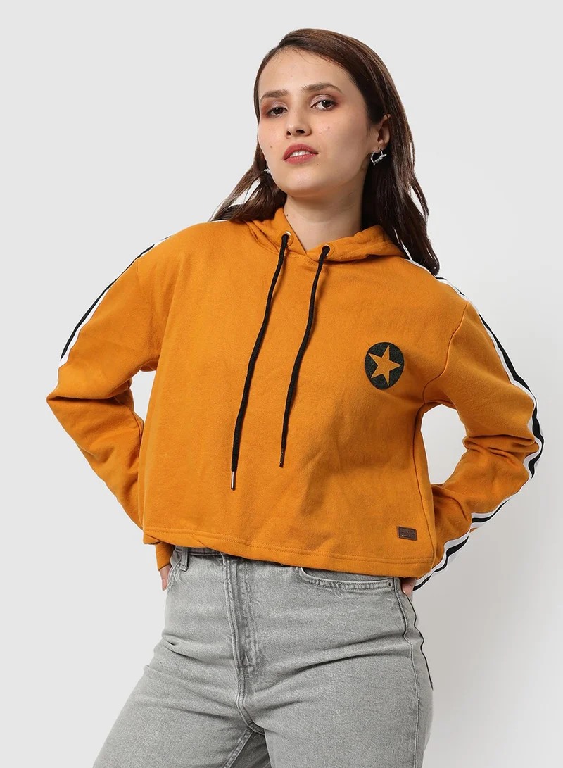 Campus Sutra Women's Mustard Yellow Star Crop Hoodie With Stripe Sleeve For Casual Wear | Hood Neck | Long Sleeve | Drawstring Closure | Cotton Sweatshirt Crafted With Comfort Fit For Everyday Wear | Mustard Yellow