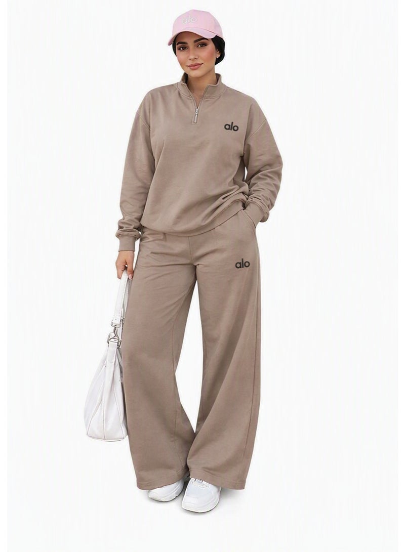 Short Description:   Women’s beige tracksuit from ALO, featuring a quarter-zip sweatshirt and wide-leg pants, designed for a stylish and comfortable everyday look.  Long Description:   Discover the perfect balance of style and comfort with the ALO Women’s Beige Tracksuit. This modern two-piece set includes a quarter-zip sweatshirt with a short collar and wide-leg pants with an elastic waistband and adjustable drawstrings. Crafted from premium soft fabric, it ensures breathability and all-day comfort. The printed ALO logo on the chest and thigh adds a chic brand touch. Ideal for workouts, running, or casual outings when paired with white sneakers for a trendy sporty look. - Image 1