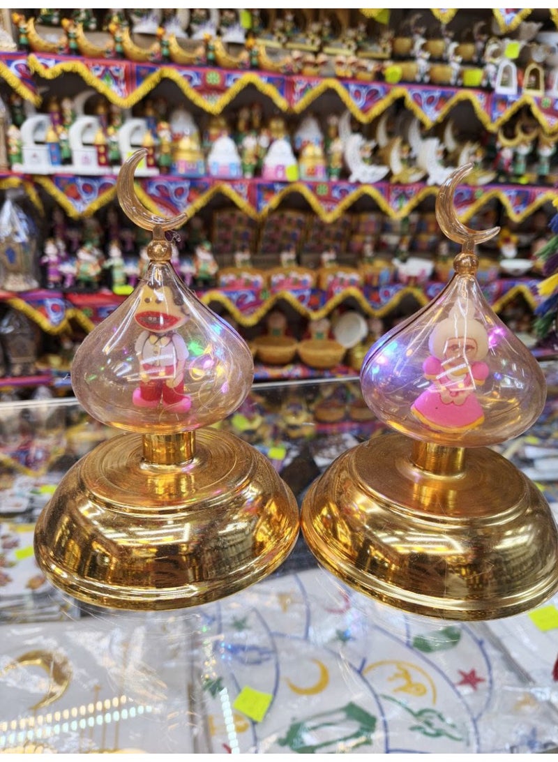 فانوس رمضان بقاعدة ذهبية وقبة زجاجية مع زخرفة هلال وشخصية فنانيس