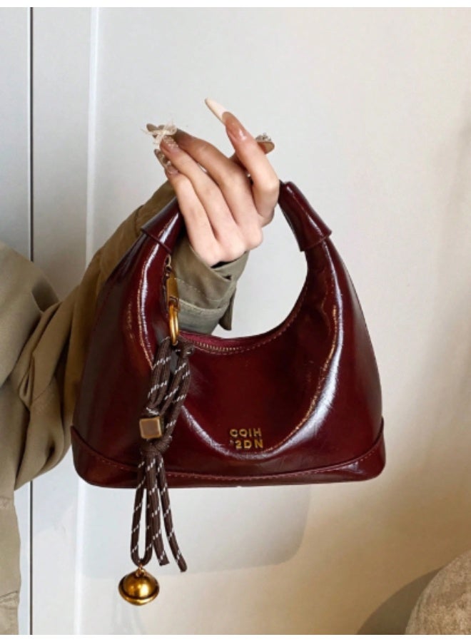 arab This mini women's shoulder bag features a glossy faux leather finish and a compact, elegant design – perfect for daily outings or special occasions. Comes in a rich burgundy color with a stylish tassel and gold-tone bell charm. Equipped with a secure top zipper and soft inner lining to protect your essentials.  Features:  Material: Glossy high-quality PU leather  Closure: Sturdy top zipper  Inner lining for added protection  Decorative tassel charm included  Lightweight and compact  Great for parties, dinners, and daily use  - Image 1