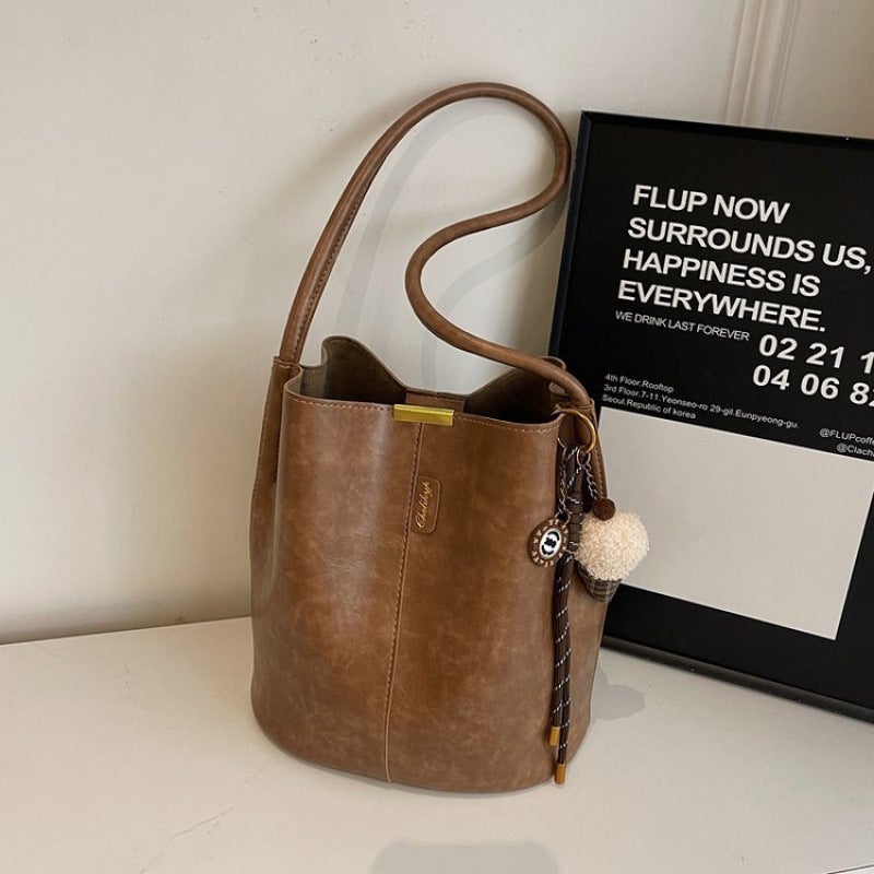 The Retro Bucket Bag Is Decorated With A Playful Fur Ball Pendant. It Can Be Worn On One Shoulder Or Cross-Body, Unlocking A Lazy And Fashionable Feel - Image 1