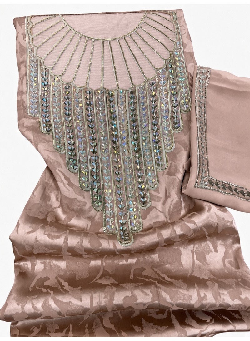 Mukhawar – Elegant Light Brownish-Pink Jacquard Silk Dress (Unstitched)  Premium light brownish-pink jacquard silk Mukhawar featuring intricate hand-finished embroidery with sparkling crystals on the neckline. The luxurious jacquard silk fabric has a soft sheen and subtle floral pattern that catches the light beautifully.  Includes a matching embroidered scarf and sleeves with detailed crystal embroidery. An elegant embroidered choker is available as an optional accessory.  Perfect for special occasions, Eid, weddings, or formal gatherings. Soft, comfortable, and richly detailed. - Image 1