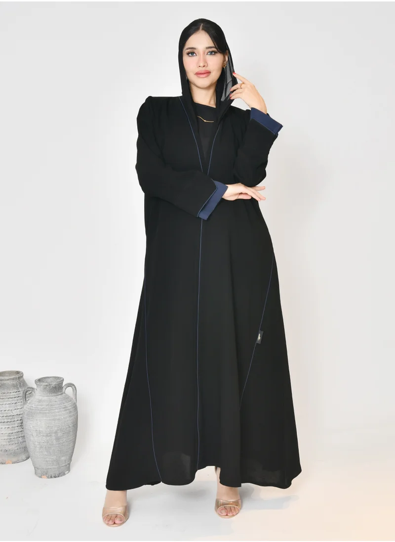 HAWRAA ABAYA Black wrap abaya with quarter-cloth fabric, puff sleeves, and navy color overlapping on the sleeves and the front and side edges of the abaya in an arrow shape