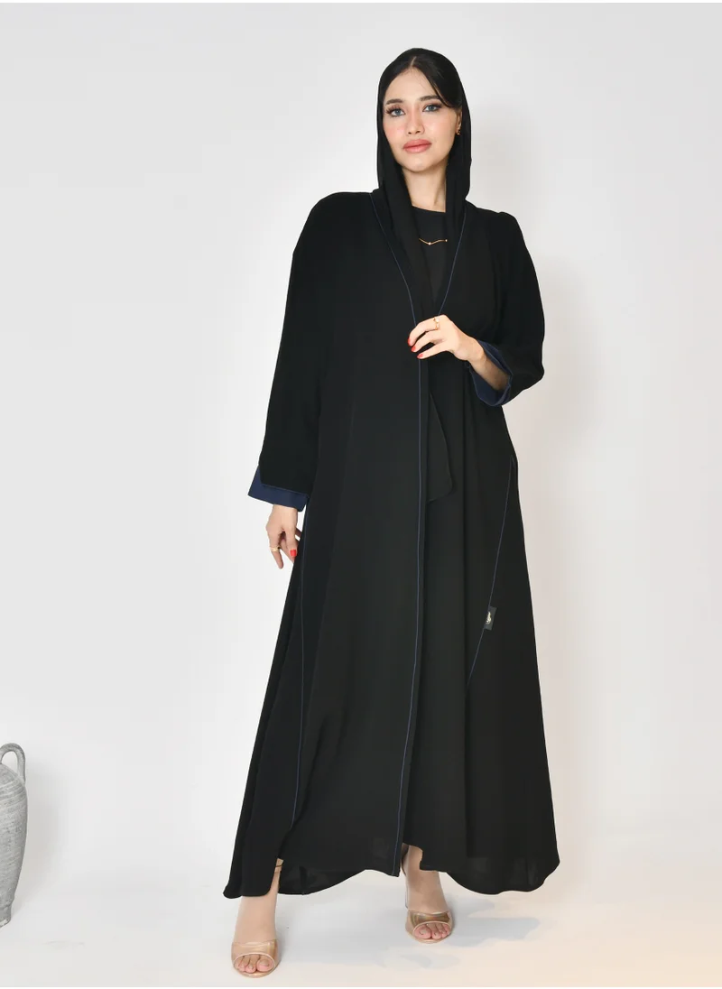 HAWRAA ABAYA Black wrap abaya with quarter-cloth fabric, puff sleeves, and navy color overlapping on the sleeves and the front and side edges of the abaya in an arrow shape