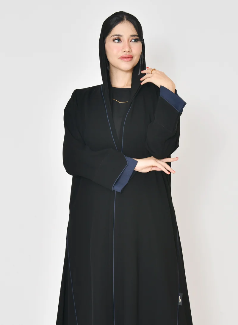 HAWRAA ABAYA Black wrap abaya with quarter-cloth fabric, puff sleeves, and navy color overlapping on the sleeves and the front and side edges of the abaya in an arrow shape