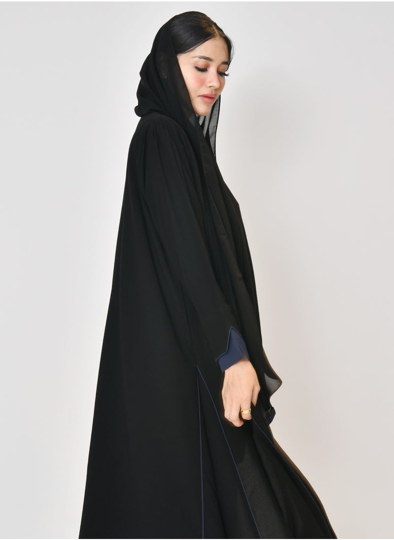 Black wrap abaya with quarter-cloth fabric, puff sleeves, and navy color overlapping on the sleeves and the front and side edges of the abaya in an arrow shape