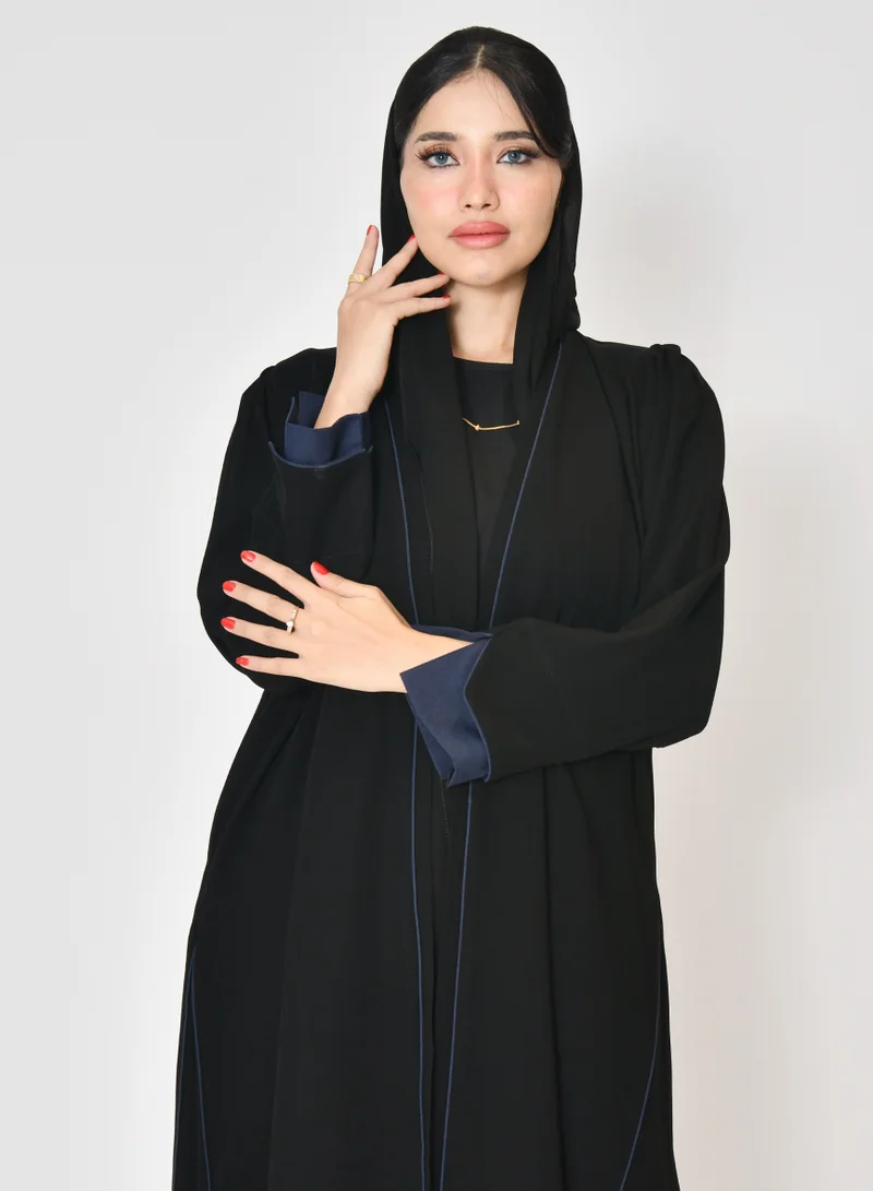 HAWRAA ABAYA Black wrap abaya with quarter-cloth fabric, puff sleeves, and navy color overlapping on the sleeves and the front and side edges of the abaya in an arrow shape