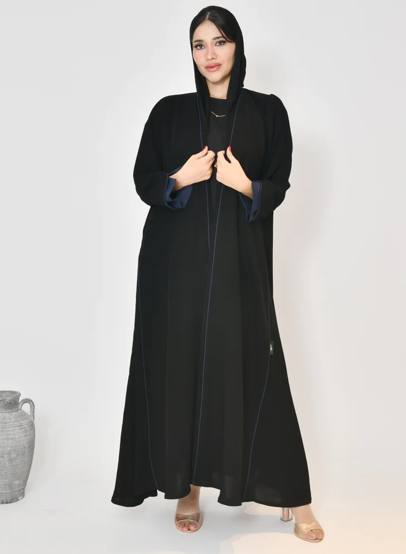 HAWRAA ABAYA Black wrap abaya with quarter-cloth fabric, puff sleeves, and navy color overlapping on the sleeves and the front and side edges of the abaya in an arrow shape
