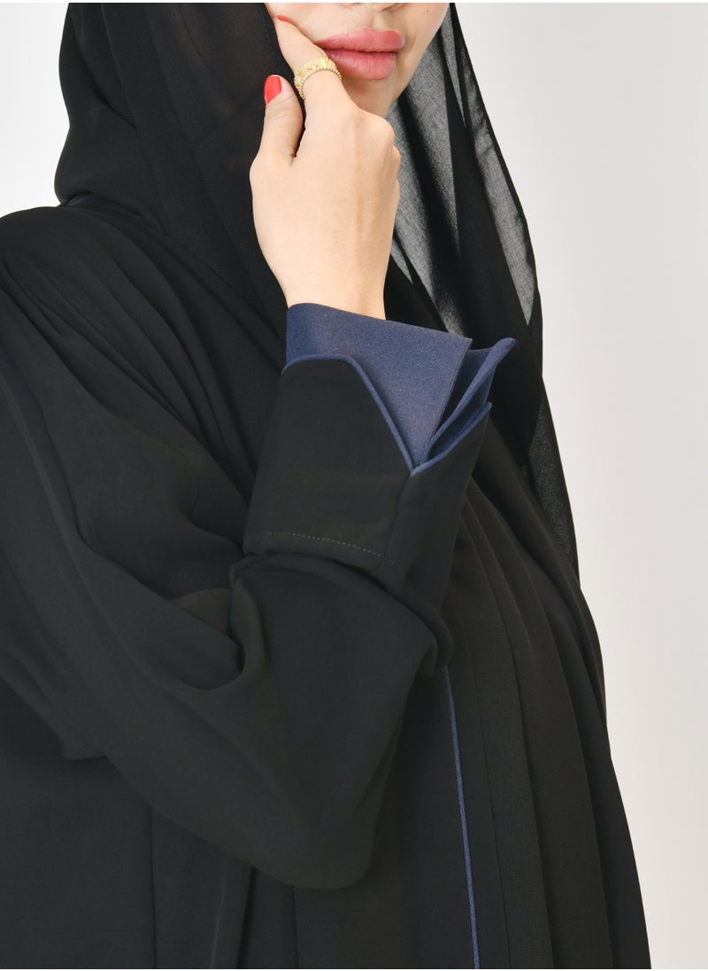 Black wrap abaya with quarter-cloth fabric, puff sleeves, and navy color overlapping on the sleeves and the front and side edges of the abaya in an arrow shape