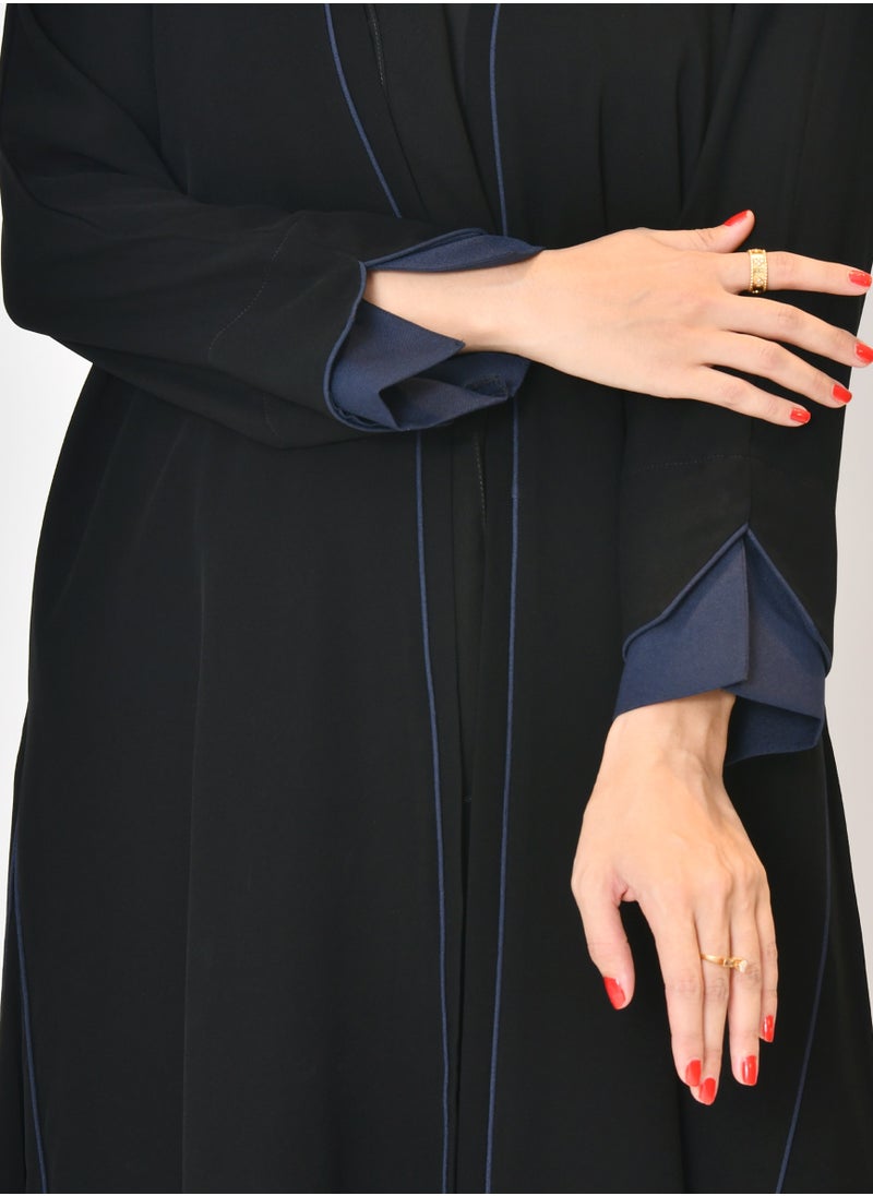 Black wrap abaya with quarter-cloth fabric, puff sleeves, and navy color overlapping on the sleeves and the front and side edges of the abaya in an arrow shape