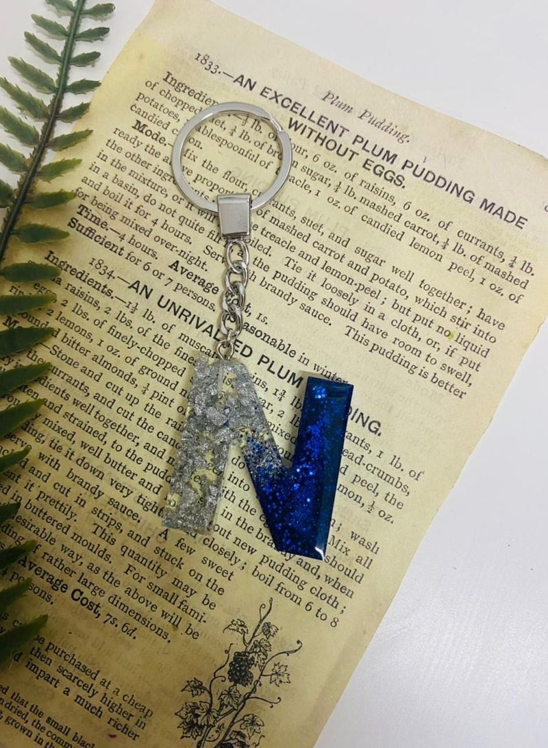 An elegant keychain with the letter N made of luxurious resin embroidered with silver leaf