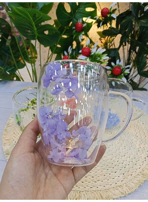 A double-walled glass mug decorated with dried flowers in an elegant design, keeps the drink hot and adds a touch of beauty to the coffee table.
