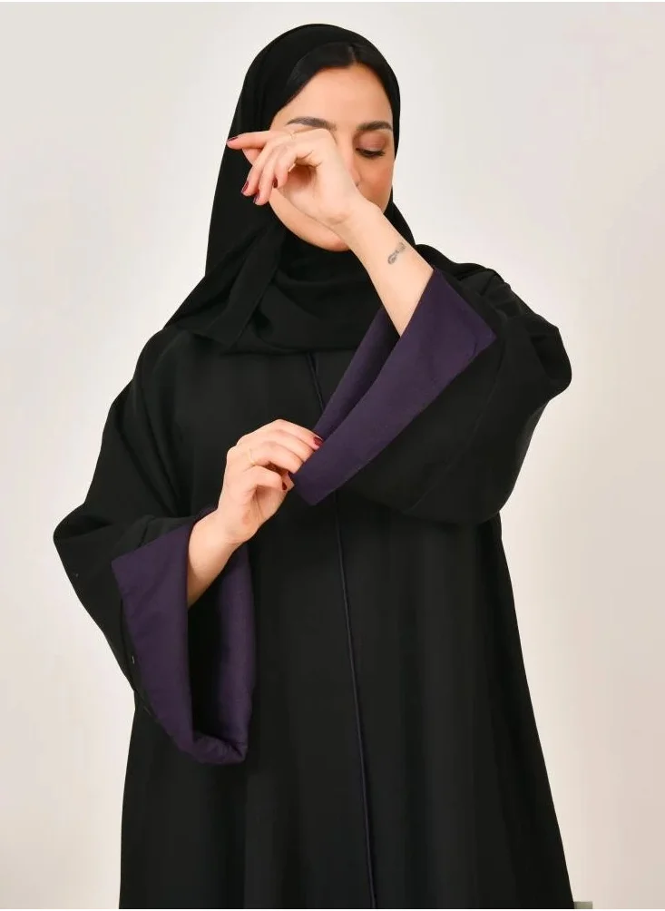 lamha abaya Black cloche abaya with prominent purple embroidery at the bottom of the abaya