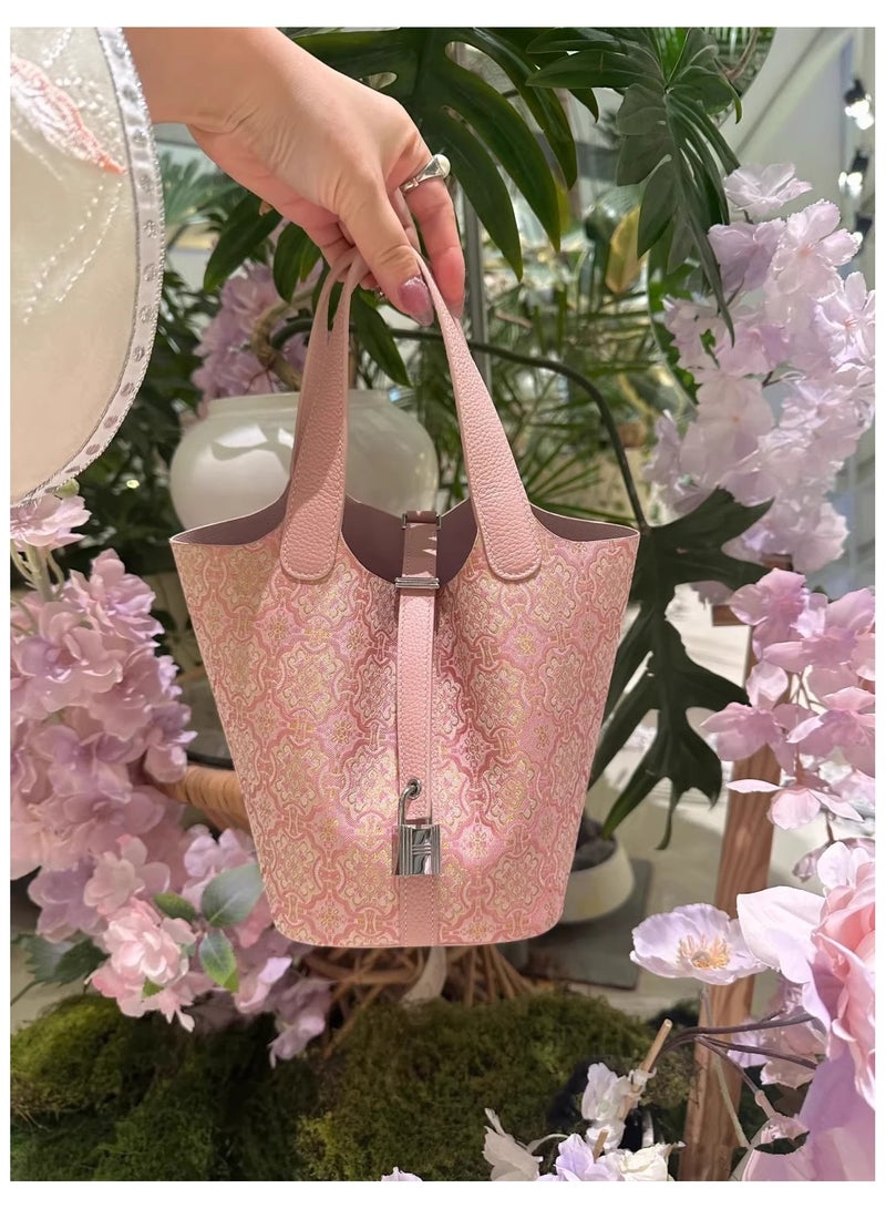 كيفية حقيبة دلو أنيقة بلون وردي فاتح، تتميز بقماش ناعم، وتفاصيل زهور ذهبية، وسحر زخرفي. مثالية للاستخدام اليومي أو المناسبات الخاصة، وتضفي لمسة من الرقي والأناقة على أي إطلالة. - Image 1