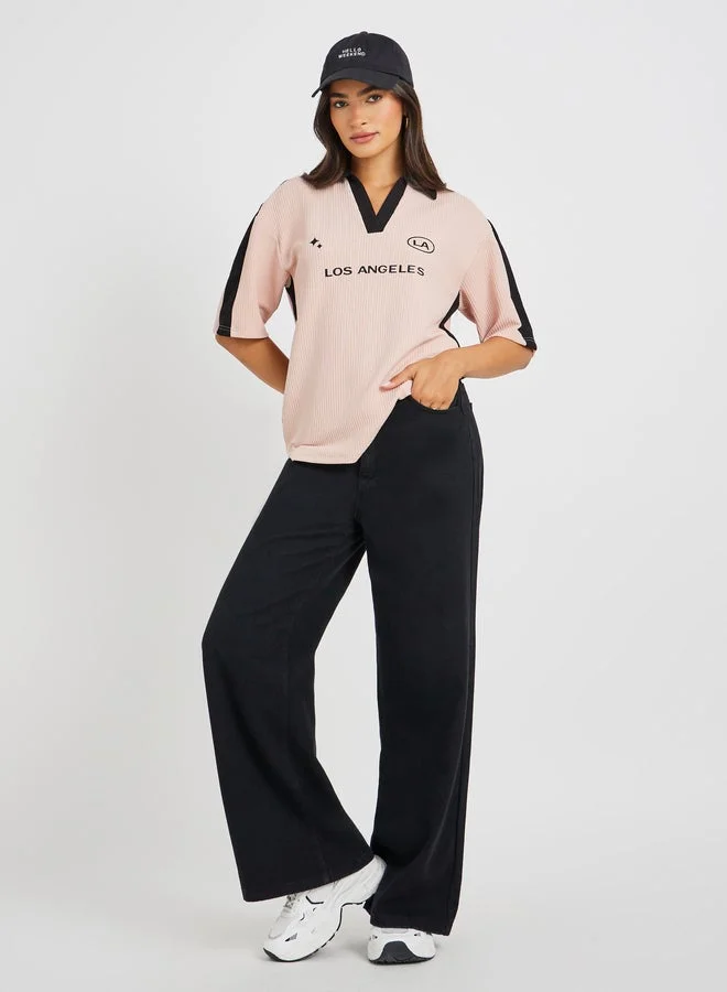 ستايلي تيشيرت فضفاض بياقة وأكمام قصيرة مطبوع عليه شعار