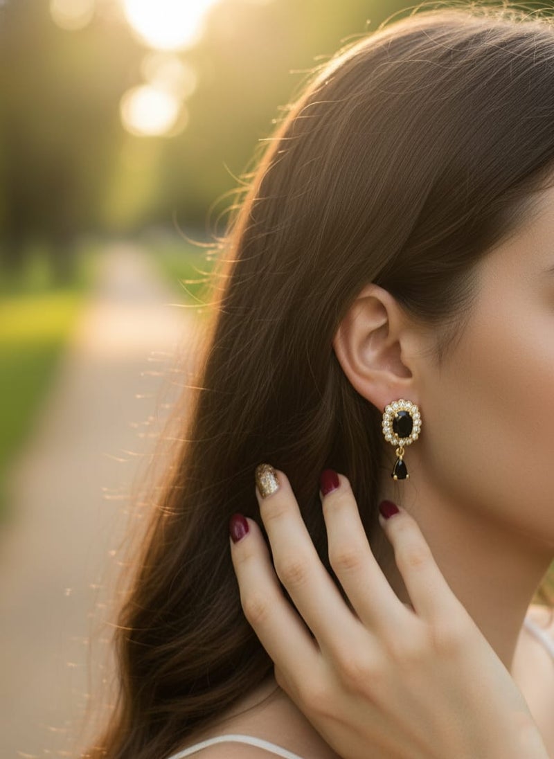 A delicate gold-plated earring featuring a golden flower design studded with shiny stones, a luxurious black stone in the middle, and a luxurious black teardrop stone hanging from it. - Image 3
