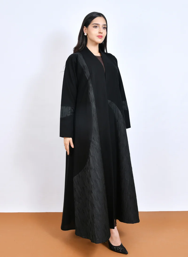 HAWRAA ABAYA Luxurious black abaya with a distinctive cloche cut, featuring embossed jacquard fabric with an arched design on the sides and sleeves.