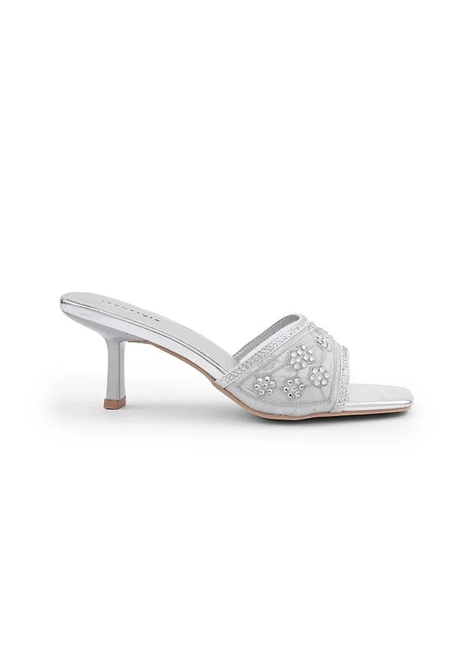 أيقون Shiny heel slipper with decorative bow accent.