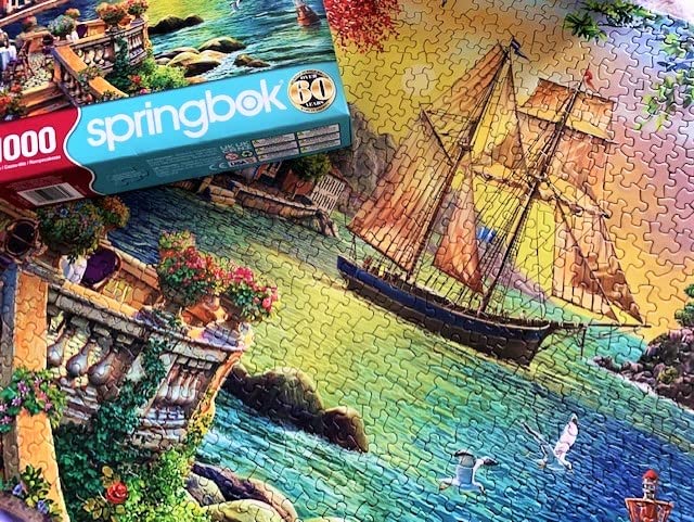 Springbok - Oceanside Sunset - 1000 Piece Jigsaw Puzzle Illustration of Villa on Waters Edge with Ship Sailing in - Image 2