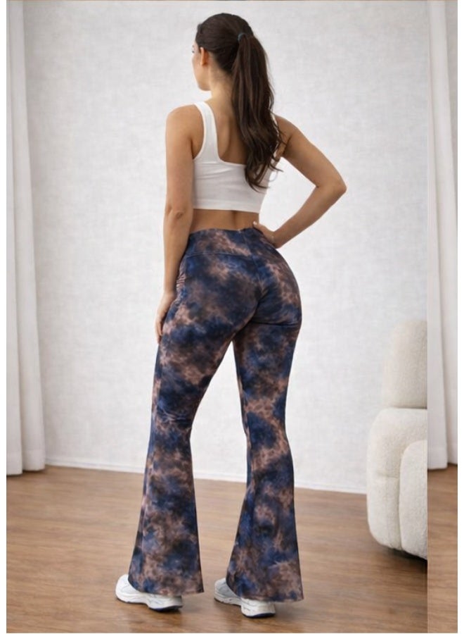 Women's pants with a high waist and a wide cut at the bottom, featuring a modern tie-dye pattern in blue and brown colors. Made from comfortable stretchy fabric suitable for everyday and casual looks. It is styled with a white sleeveless crop top for a chic and trendy look. White sneakers add a youthful and practical touch. Suitable for wearing at home or going out with friends. - Image 2
