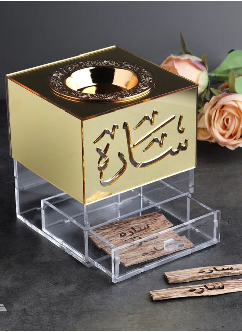 An Incense Burner Made of Transparent and Shiny Gold Acrylic with a Drawer for Storing Incense. It Comes with an Arabic Name.