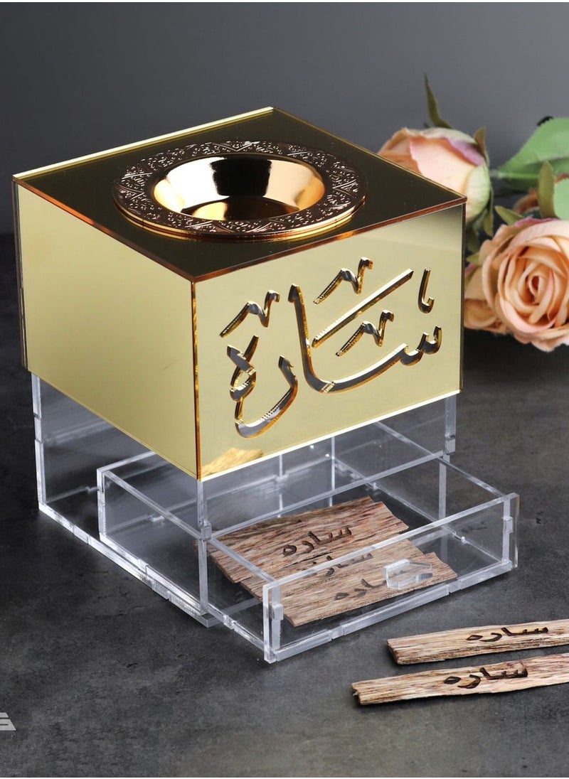 An Incense Burner Made of Transparent and Shiny Gold Acrylic with a Drawer for Storing Incense. It Comes with an Arabic Name.