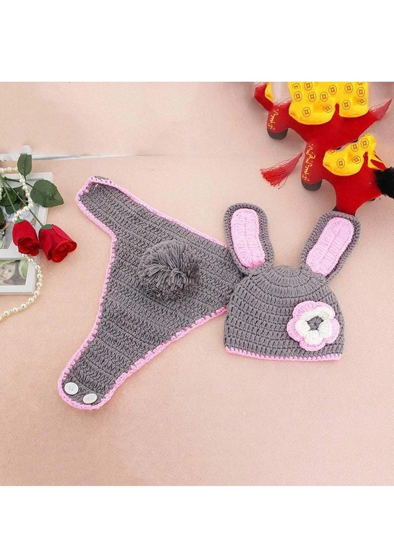 A crocheted baby boy consisting of a small hat with a bunny ears design decorated with a prominent rose, in addition to another piece used as a cover or comfortable clothing that is closed with buttons. The basic color of the set is light gray with pink edges, giving it an elegant and soft look suitable for children.