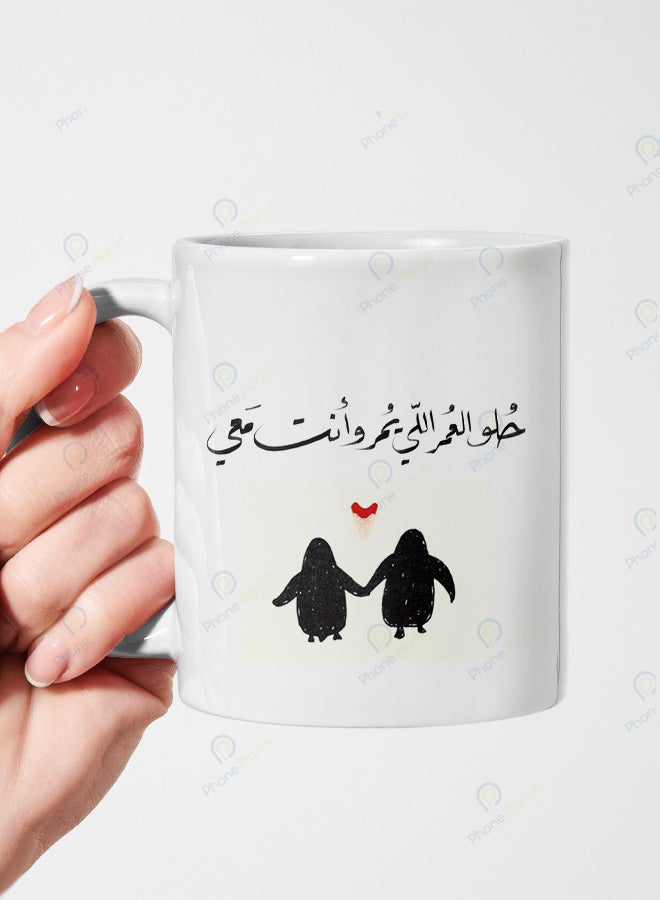 كوب من السيراميك مطبوع عليه عبارة حلو العمر اللي يمر وأنت معي ويتميز بمقبض مريح